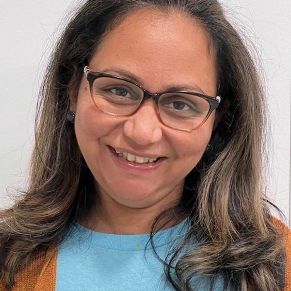 Smiling woman wearing glasses and a blue shirt.