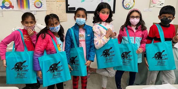 Group of kids holding blue Crazy Colors art studio bags.