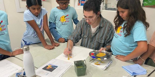 A group of kids watching an adult paint during an art class.
