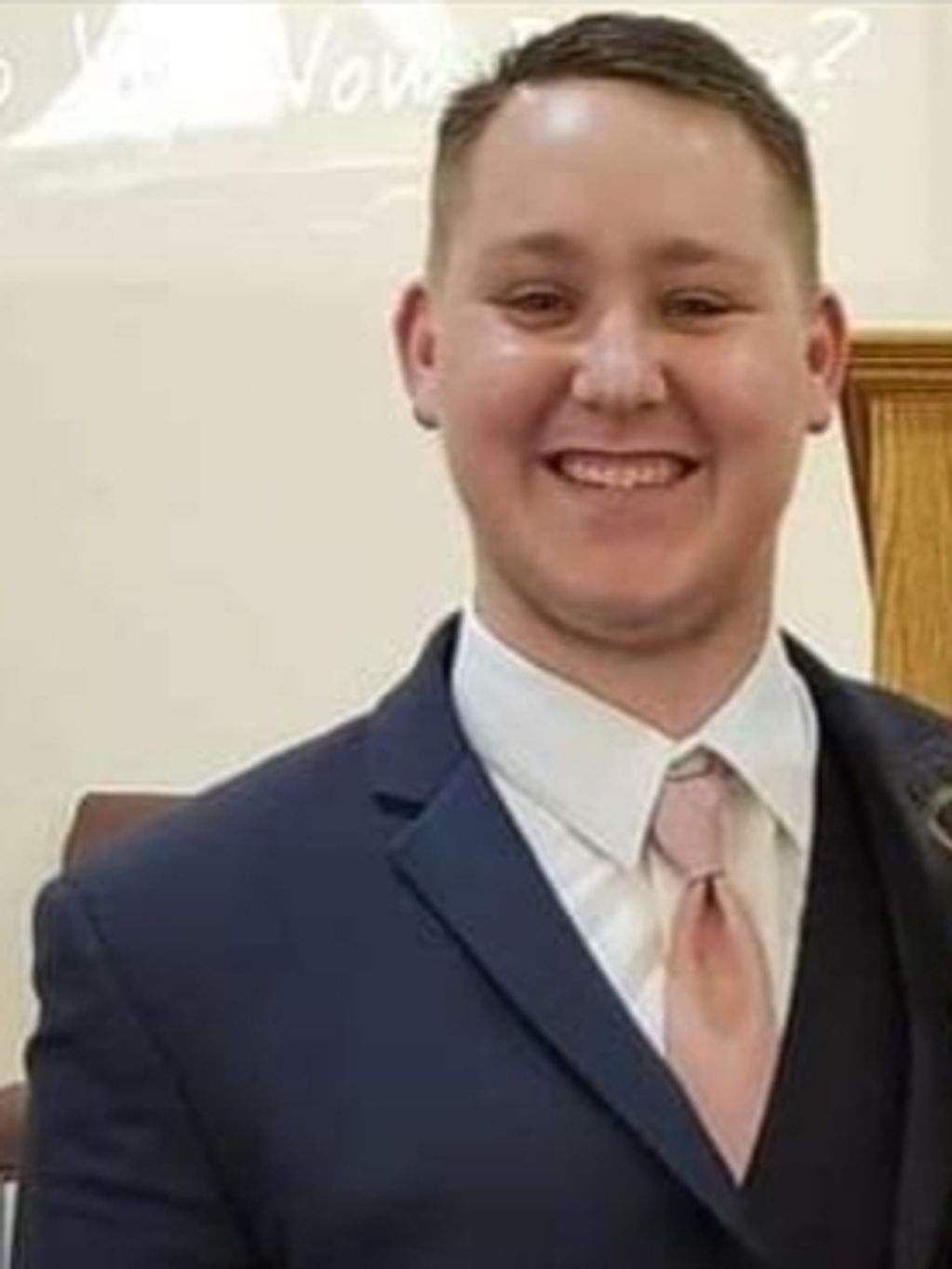 Young man smiling in a suit and tie.