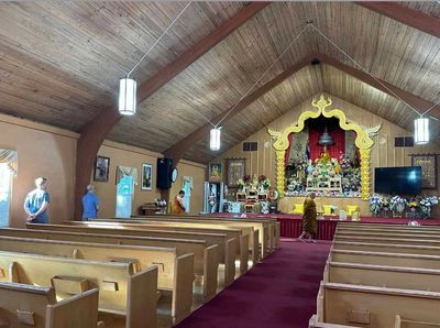 Interior of a Buddhist temple with a monk and worshippers.