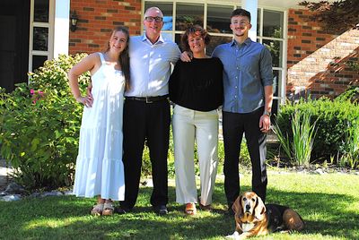 Une famille de quatre personnes avec un chien dans un jardin.