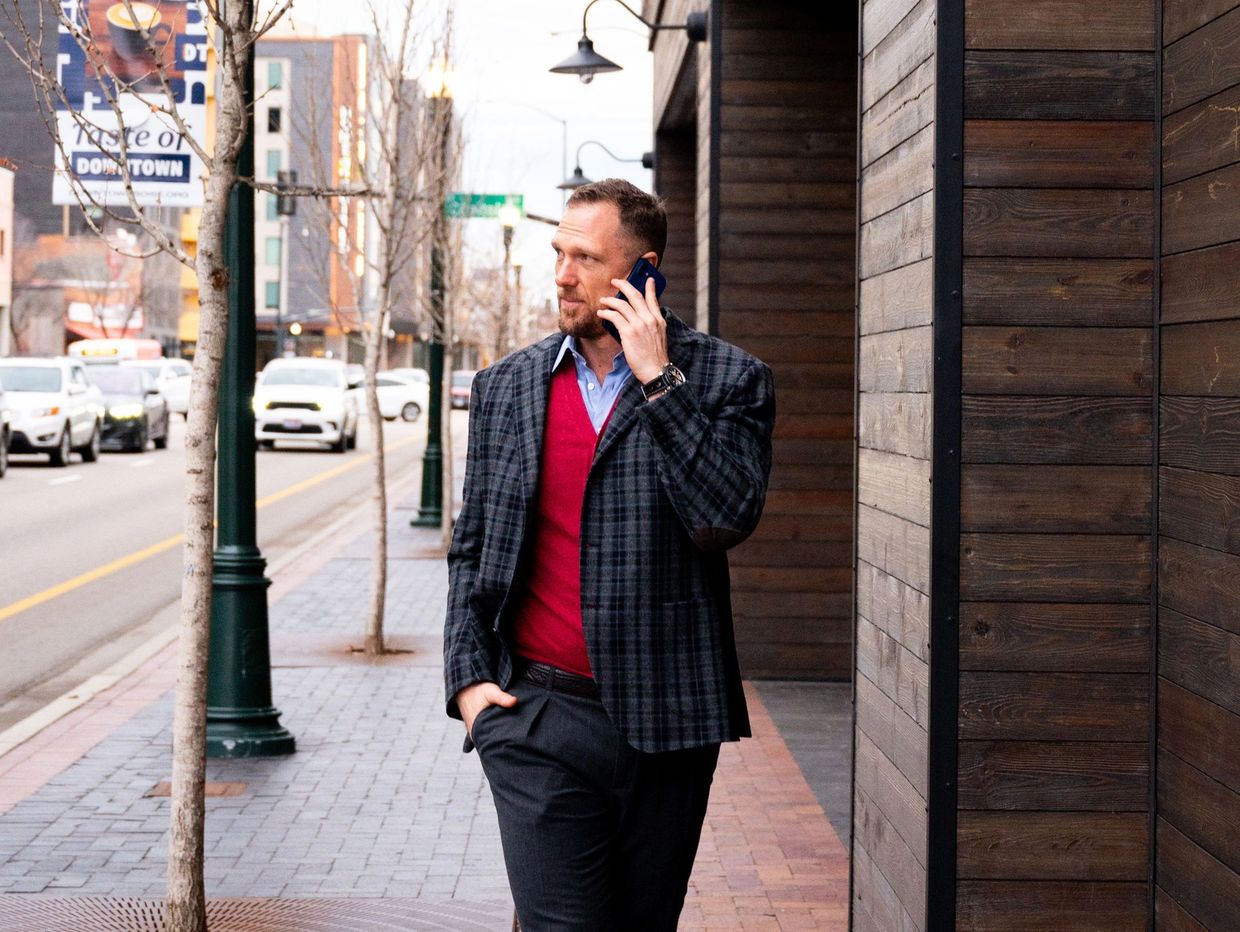 Man in stylish outfit walking and talking on phone in urban street.