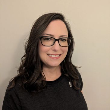 Smiling woman with glasses wearing a black Reebok t-shirt.