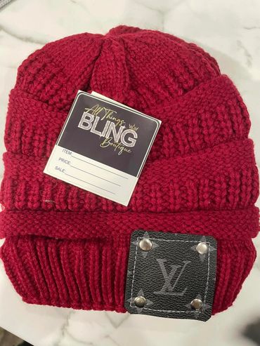 Red knit beanie with a tag and logo patch.