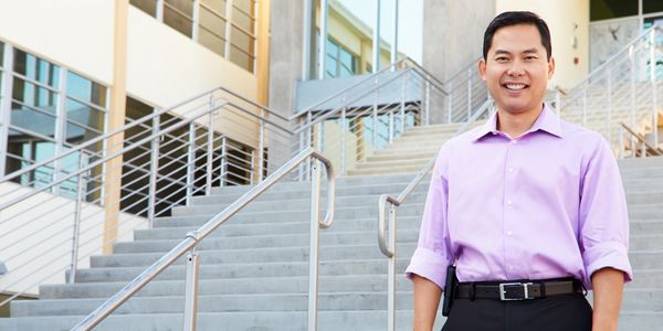 School leader standing on outsides stairs of campus.