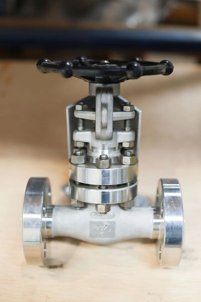 Close-up of a metallic industrial valve with a black handwheel.