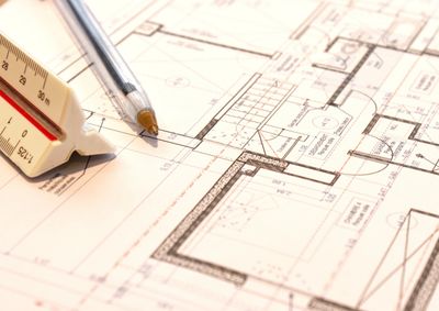 Architectural blueprint with pen and scale ruler on table.