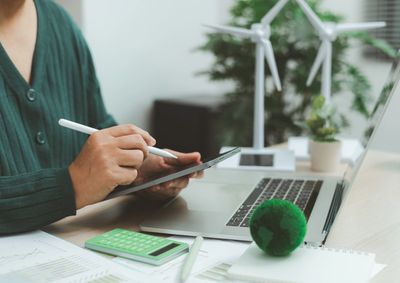 Person using a stylus on a tablet at a sustainable workspace.