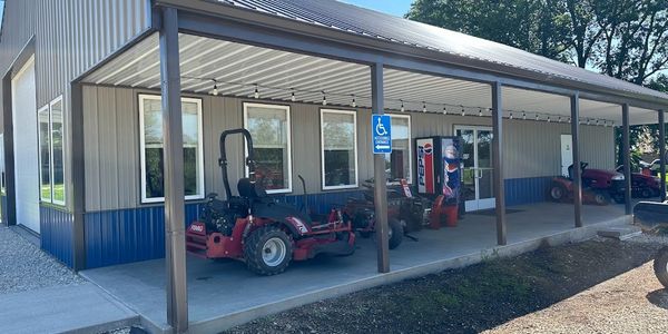 Metal shop with lawn mowers and a soda machine. 