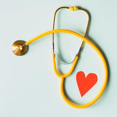 Yellow stethoscope encircling red paper heart