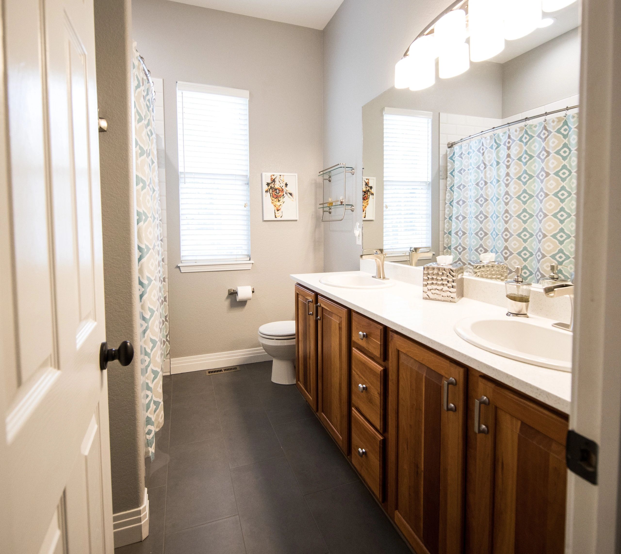 Double sink vanity and white toilet in white painted bathroom with blue and white shower curtain