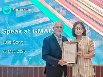 Two people posing with a certificate at GMAC event.