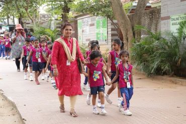 Teacher leading a group of young students on a school outing.