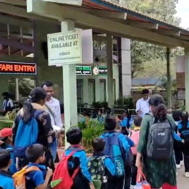 Children and adults queue at safari entry with backpacks.