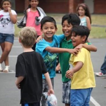 Children happily playing and hugging outdoors on a sunny day.