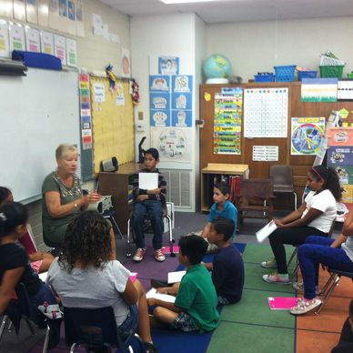 Teacher reading to a group of attentive children in a classroom circle.