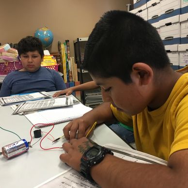 Two boys working on an electrical project in a classroom.