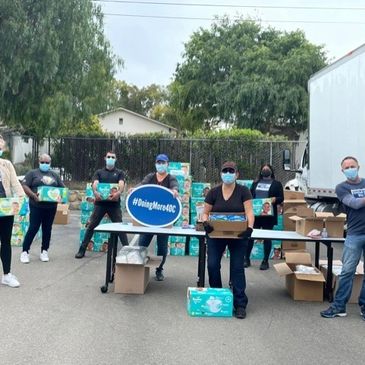 Group of people wearing masks distributing boxes outdoors.