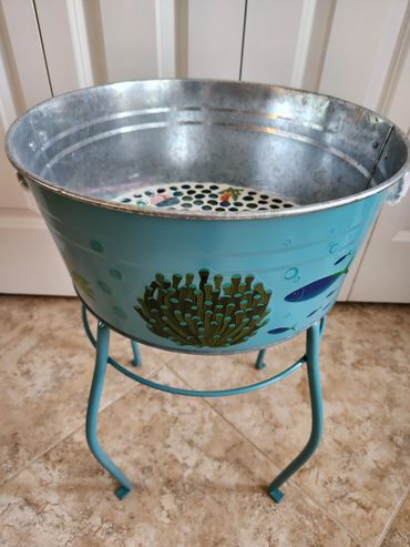 Metal bucket with aquatic design on a blue stand.