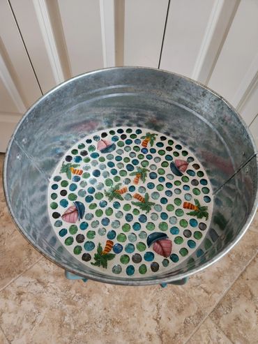 Metal bucket with decorated bottom featuring carrots and shells.