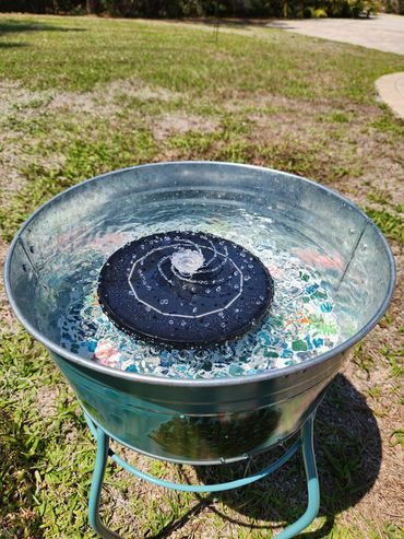 Outdoor metal water fountain with a spiral design on top.