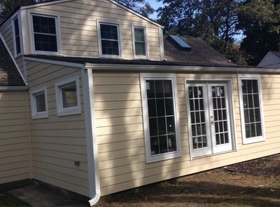Yellow two-story house with white-framed windows and French doors.