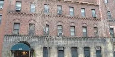 Brick apartment building with multiple windows and air conditioners.