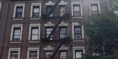 Brick apartment building with fire escape and window air conditioners.