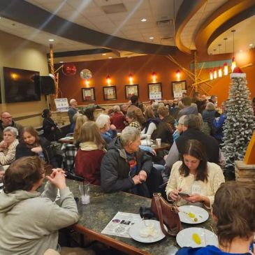 Crowded restaurant with people dining and conversing.