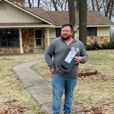 Man holding a box outside a house on a gloomy day.