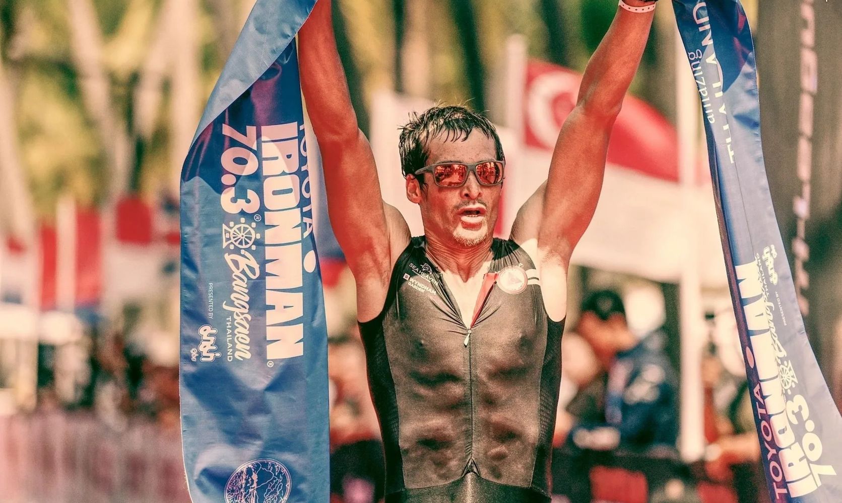 Triathlete celebrating finishing the Ironman 70.3 race in Thailand.