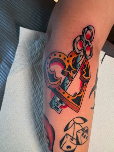 Colorful heart-shaped lock and key tattoo on forearm.