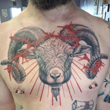Detailed ram tattoo with red barbed wire on chest.