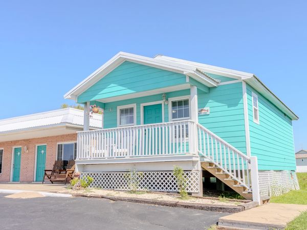 A small, teal-colored building with a white balcony and stairs