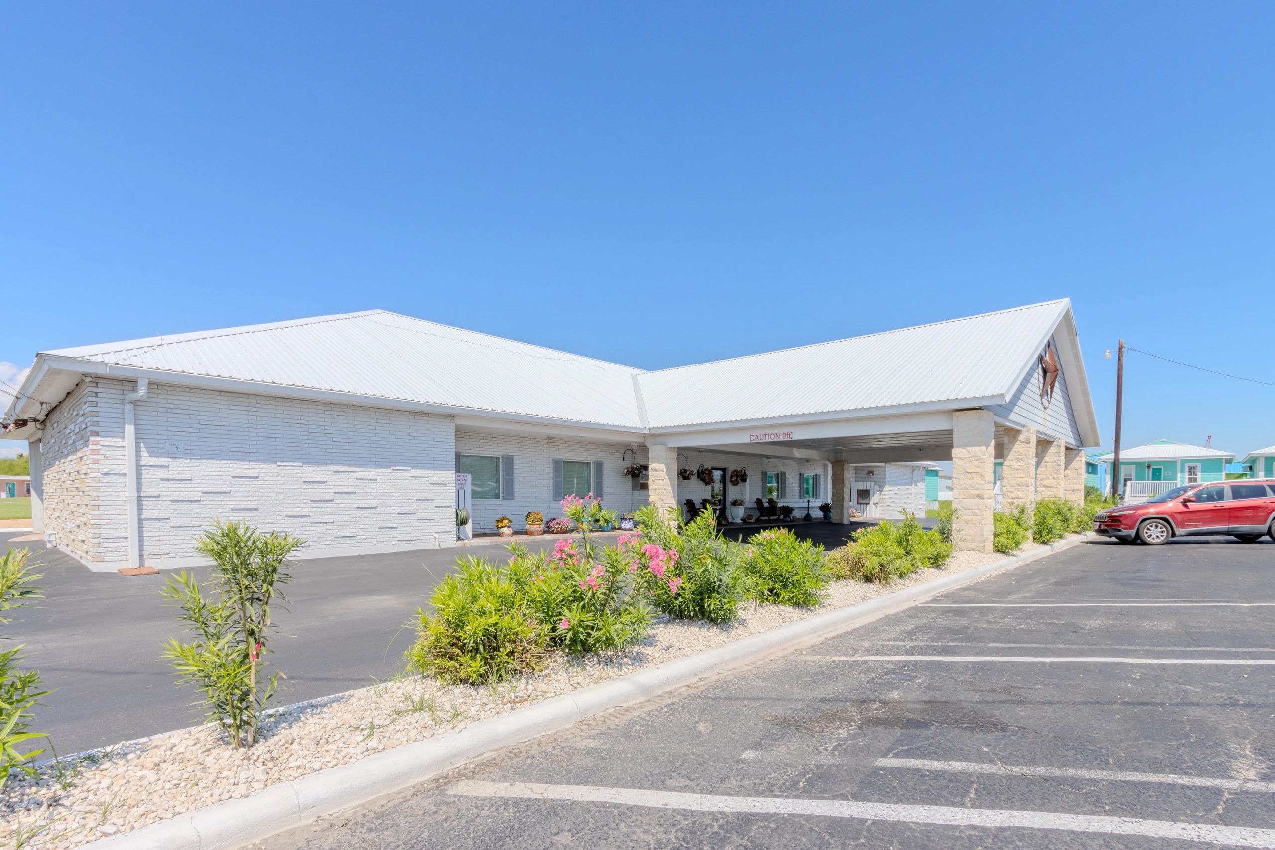 A single-story white building with a parking lot and landscaping.
