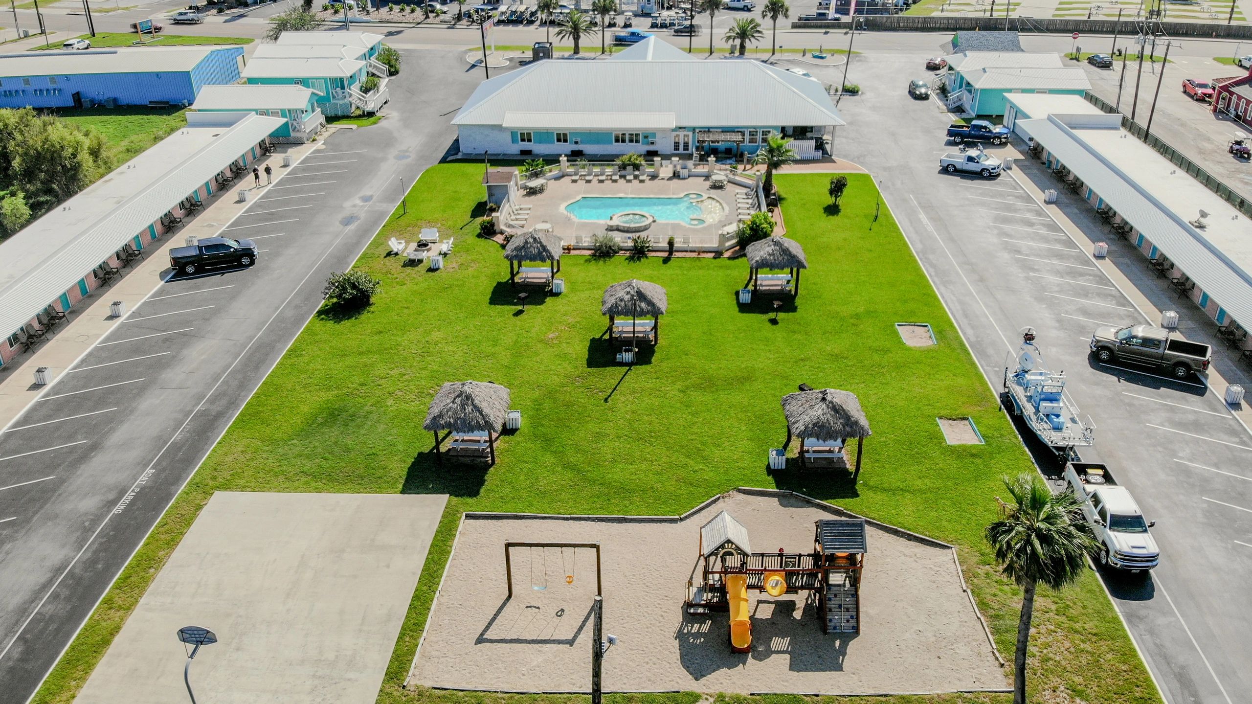 Aerial view of a hotel resort with a pool, playground, and parking lot.