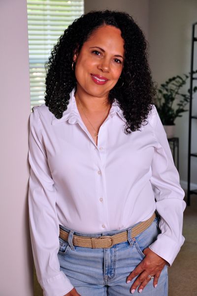 An image of Malika Lorie, approachable, wearing a white button down shirt and jeans. 