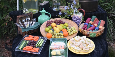 A beautifully arranged outdoor table with fresh fruits, vegetables, and decorated napkins.