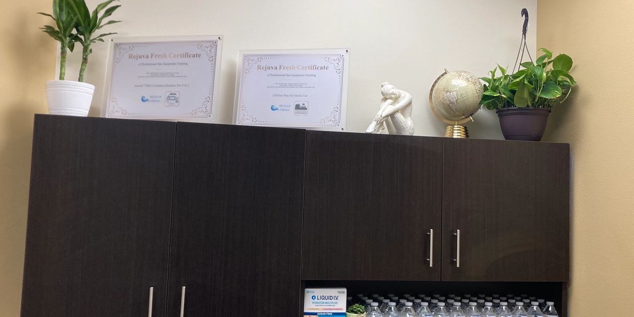 Dark cabinet with plants, certificates, globe, and bottled water on top.
