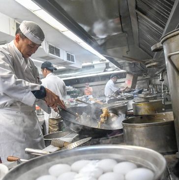 Chinese seafood chefs working in a busy restaurant kitchen, cooking multiple dishes at once.