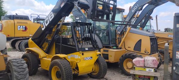 A yellow JCB 520 skid steer loader among other construction machinery.
