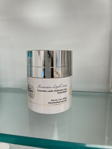 Restorative Lipid Cream jar with silver lid on glass shelf.