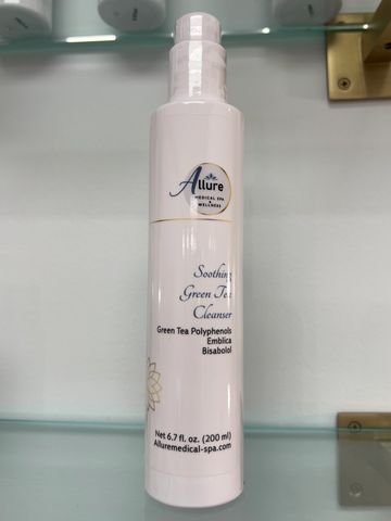 Bottle of Allure Soothing Green Tea Cleanser on glass shelf.