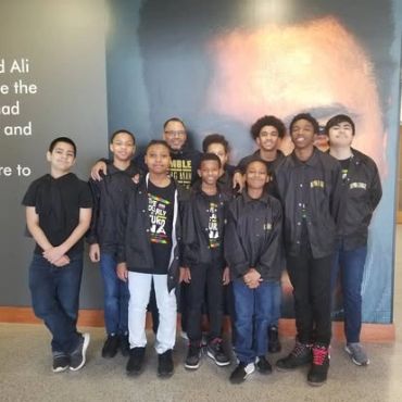 Group of boys posing indoors in front of a wall.