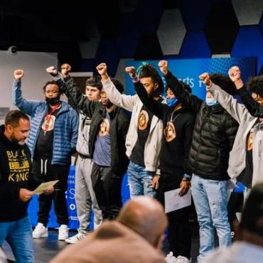 Group raising fists in solidarity during a speech.
