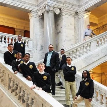 A group of students and a teacher posing on marble stairs.