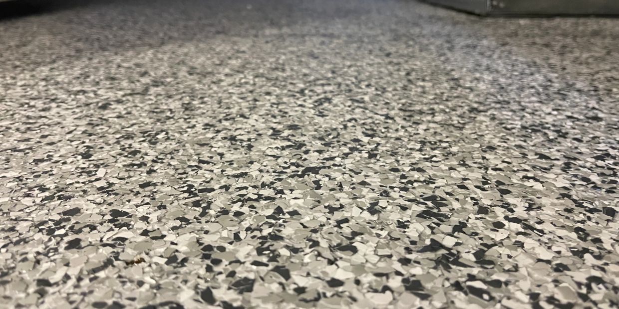 Close-up of a speckled epoxy floor in grayscale tones.