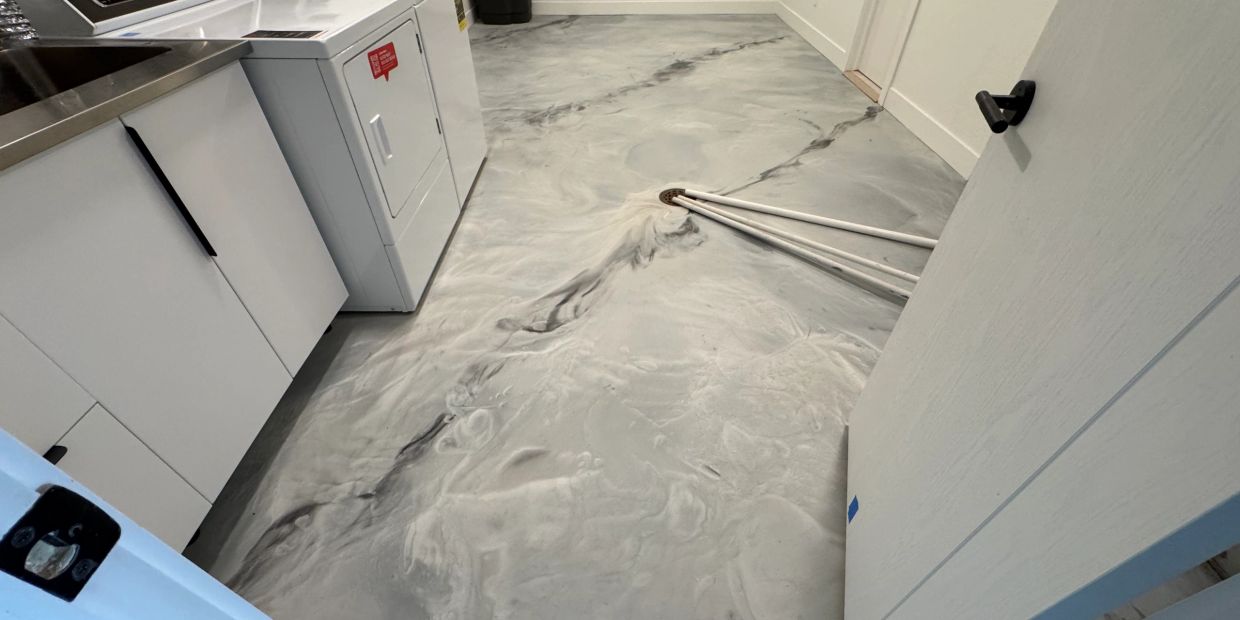 Laundry room with modern marbled epoxy flooring and white cabinets.