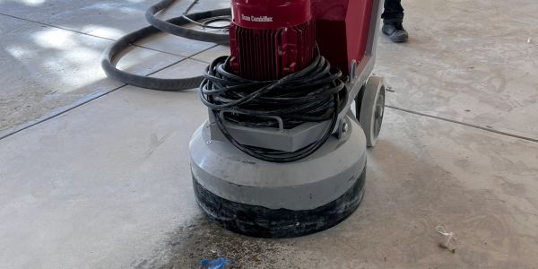Concrete floor grinding machine in use on a construction site.